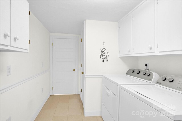 laundry area featuring baseboards, cabinet space, washing machine and dryer, and light tile patterned flooring