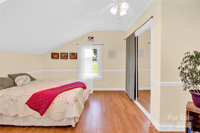 bedroom featuring baseboards, ceiling fan, wood finished floors, and lofted ceiling