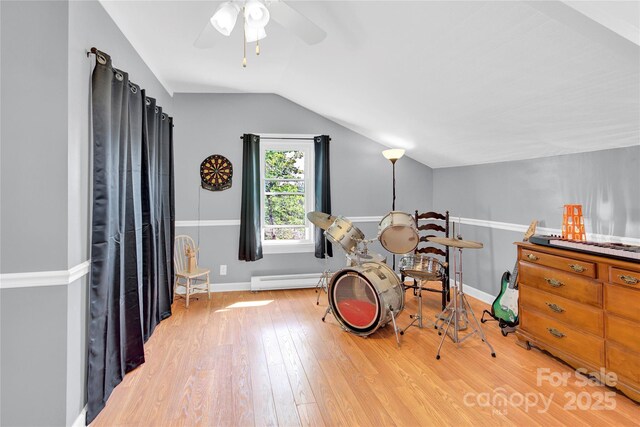 interior space featuring light wood-style flooring, a ceiling fan, baseboards, a baseboard heating unit, and vaulted ceiling