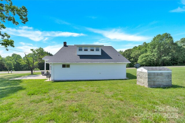 rear view of property with a patio, a yard, and a chimney