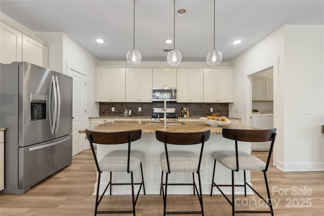 2638 Double Oaks Rd, Charlotte, NC 28206 - kitchen featuring appliances with stainless steel finishes, a sink, tasteful backsplash, light wood-style floors, and a breakfast bar area
