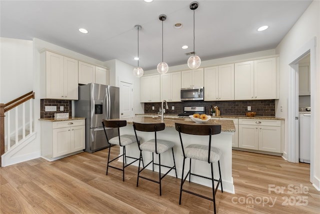 2638 Double Oaks Rd, Charlotte, NC 28206 - kitchen featuring appliances with stainless steel finishes, a kitchen bar, tasteful backsplash, light wood-style flooring, and recessed lighting