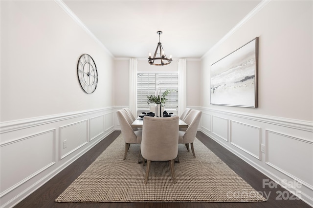 dining space with a decorative wall, dark wood-style flooring, a chandelier, ornamental molding, and wainscoting