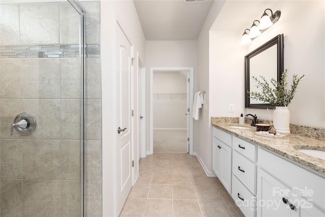 bathroom with a stall shower, a spacious closet, double vanity, and tile patterned floors