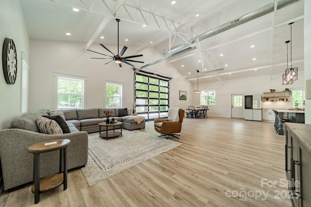 living room with beam ceiling, high vaulted ceiling, recessed lighting, a ceiling fan, and light wood-type flooring