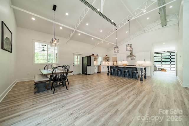 dining space with recessed lighting, high vaulted ceiling, baseboards, and light wood finished floors