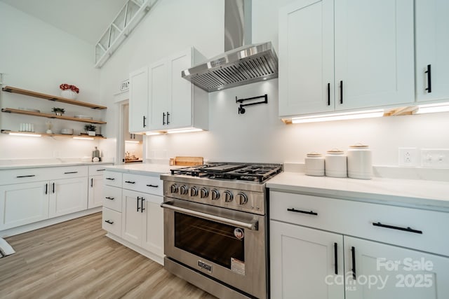 kitchen featuring wall chimney range hood, light countertops, high end stainless steel range, and white cabinetry