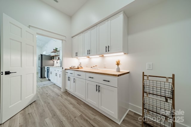 interior space with white cabinets, freestanding refrigerator, and light wood-type flooring