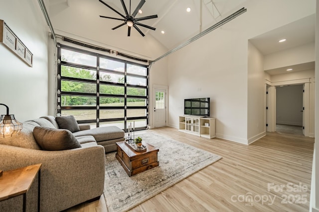 living area with a ceiling fan, high vaulted ceiling, baseboards, light wood-style floors, and recessed lighting