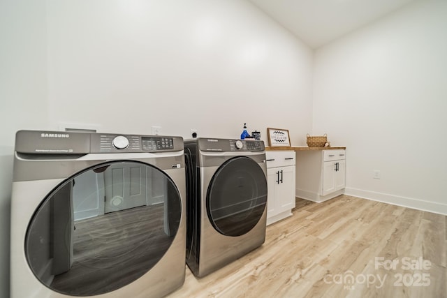 washroom featuring baseboards, light wood-type flooring, cabinet space, and washer and clothes dryer