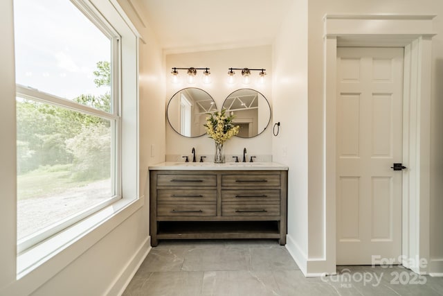 bathroom with double vanity, baseboards, and a sink