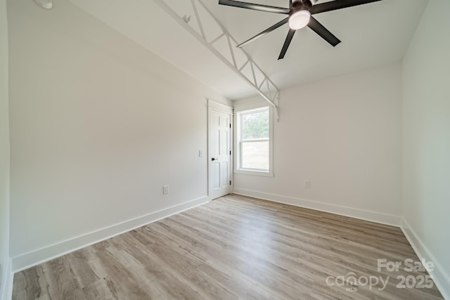 empty room featuring baseboards, a ceiling fan, and light wood-style flooring