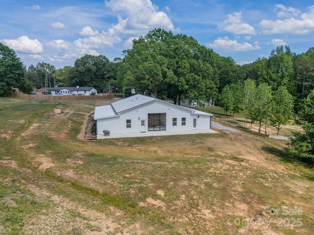 view of side of home featuring a forest view, an outbuilding, and an outdoor structure