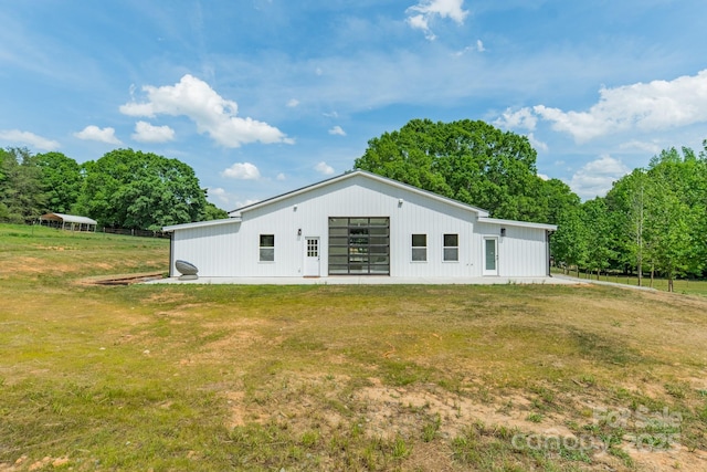 back of property with a lawn, a pole building, board and batten siding, and an outbuilding