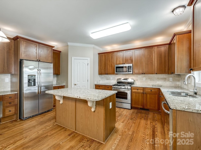 kitchen featuring crown molding, decorative backsplash, a sink, light wood finished floors, and stainless steel appliances