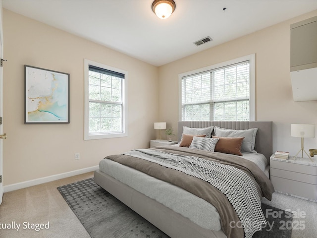 bedroom featuring baseboards, light carpet, and visible vents