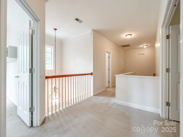 hall featuring visible vents, crown molding, carpet floors, baseboards, and an upstairs landing