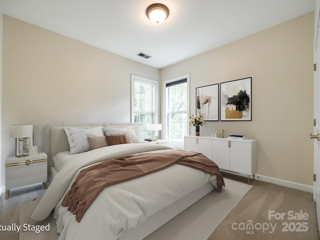 bedroom with visible vents, baseboards, and light carpet