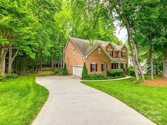 traditional home with a garage, driveway, a front lawn, and brick siding