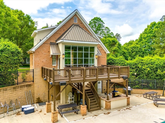 back of house featuring a wooden deck, a patio, stairs, and brick siding