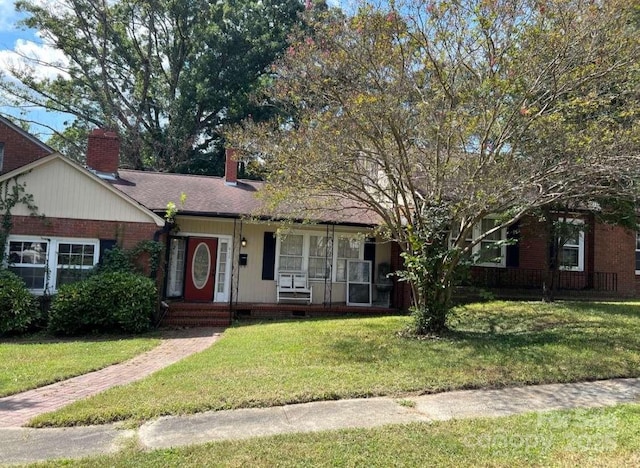 ranch-style home with a chimney, brick siding, and a front yard