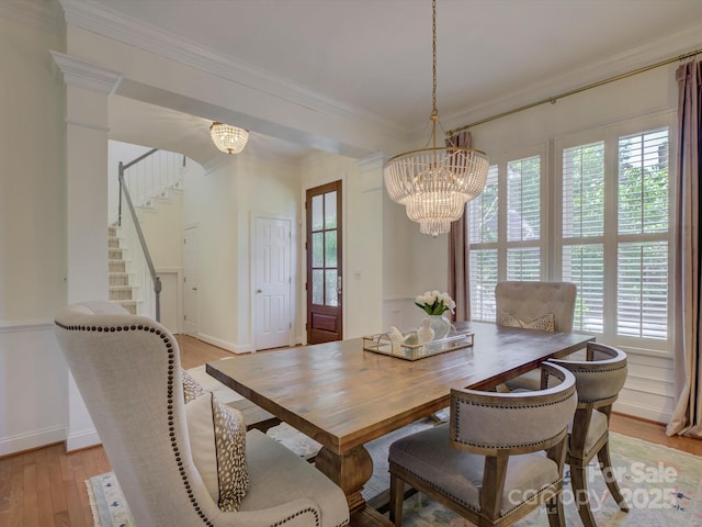 dining area featuring stairway, baseboards, a chandelier, light wood-style floors, and ornamental molding