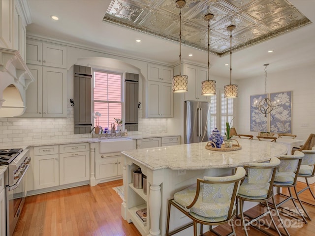 kitchen featuring a kitchen breakfast bar, high quality appliances, a center island, a sink, and backsplash