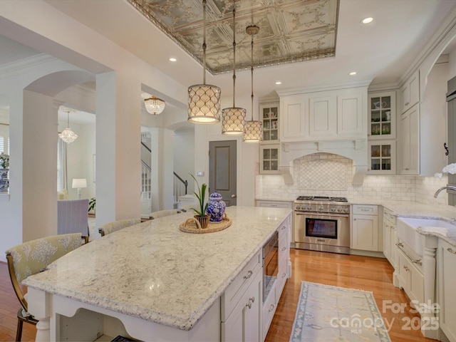 kitchen featuring a sink, arched walkways, a kitchen breakfast bar, stainless steel appliances, and tasteful backsplash