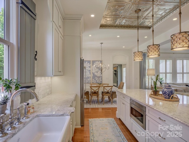 kitchen with a sink, appliances with stainless steel finishes, plenty of natural light, and light wood-style flooring