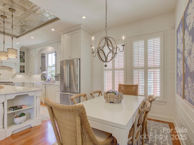 dining room featuring an inviting chandelier, arched walkways, light wood finished floors, and recessed lighting