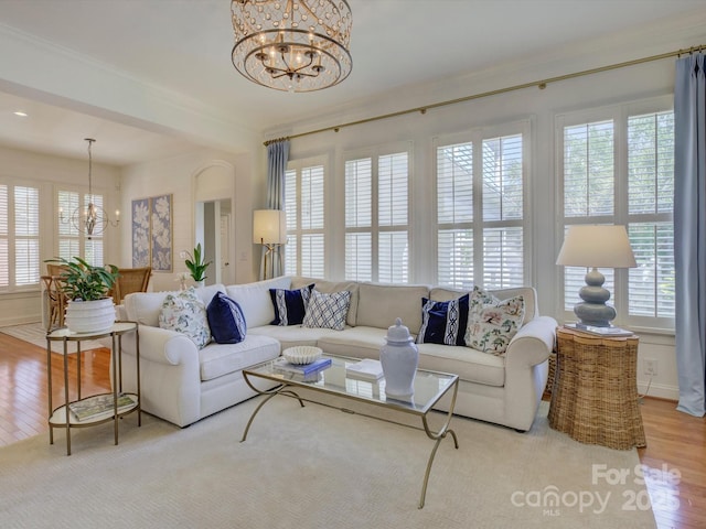 living area with baseboards, a wealth of natural light, wood finished floors, and a chandelier