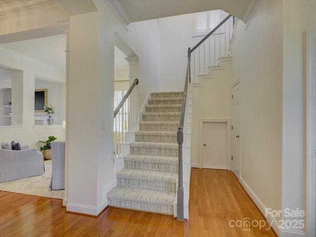 stairway with baseboards, ornamental molding, and wood finished floors