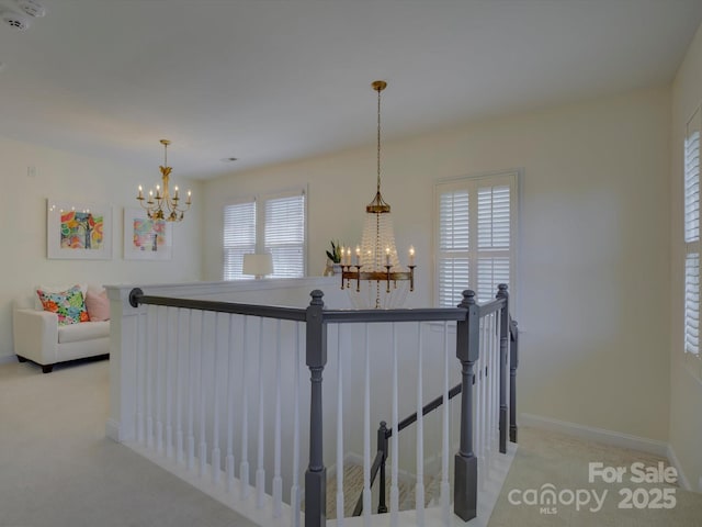 corridor with baseboards, light carpet, a notable chandelier, and an upstairs landing