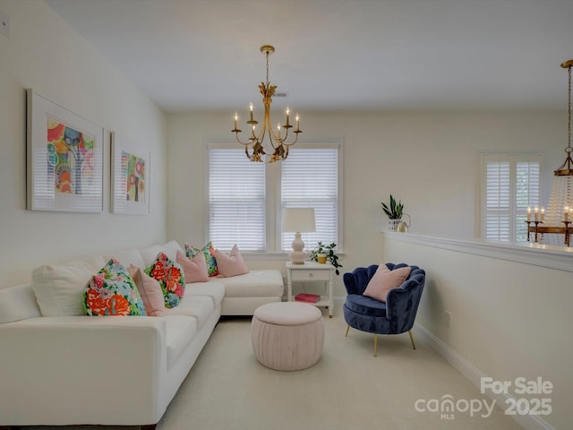 carpeted living area featuring baseboards and a chandelier