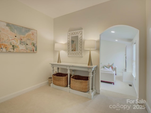 hallway featuring arched walkways, baseboards, visible vents, and carpet