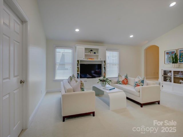 living area with light colored carpet, arched walkways, baseboards, and recessed lighting