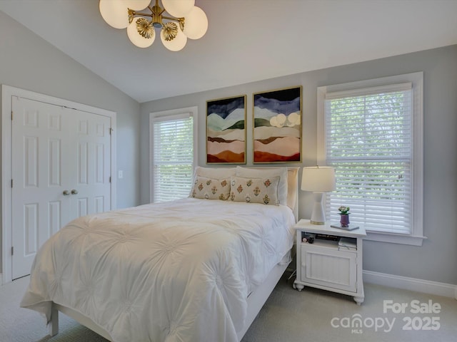 bedroom with a notable chandelier, baseboards, a closet, lofted ceiling, and light carpet