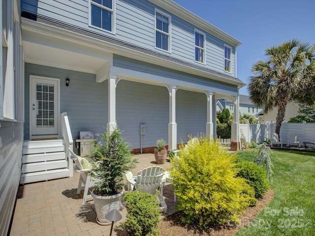 exterior space with entry steps, fence, a patio, and a lawn
