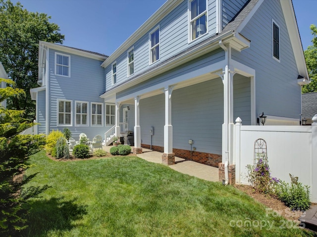 back of property with fence, covered porch, and a yard