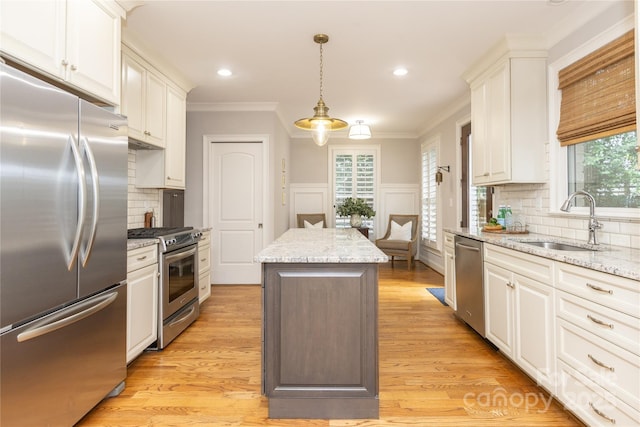 1517 Waverly Ave, Charlotte, NC 28203 - kitchen with stainless steel appliances, a sink, a kitchen island, crown molding, and white cabinetry