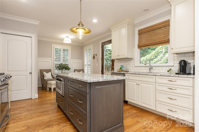 1517 Waverly Ave, Charlotte, NC 28203 - kitchen with white cabinets, light wood finished floors, decorative backsplash, crown molding, and a wainscoted wall