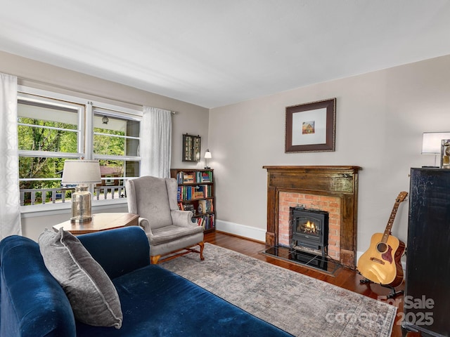 living area with a brick fireplace, baseboards, and wood finished floors