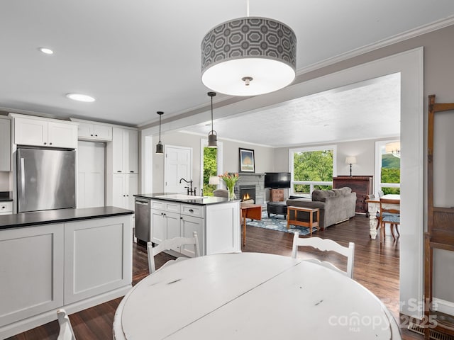 dining area with crown molding, recessed lighting, dark wood-style flooring, and a warm lit fireplace