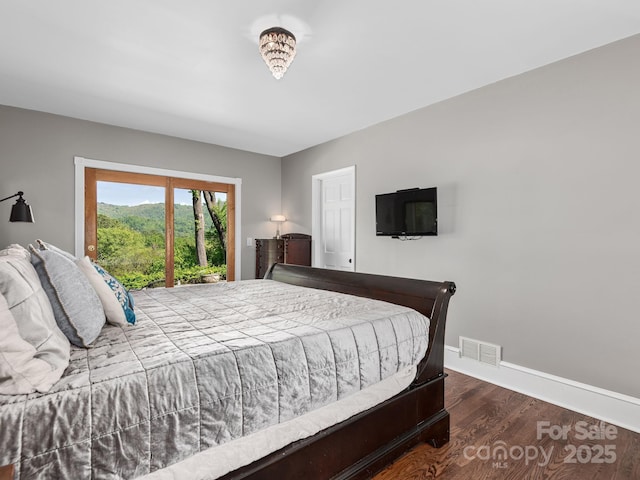 bedroom featuring baseboards, wood finished floors, and visible vents