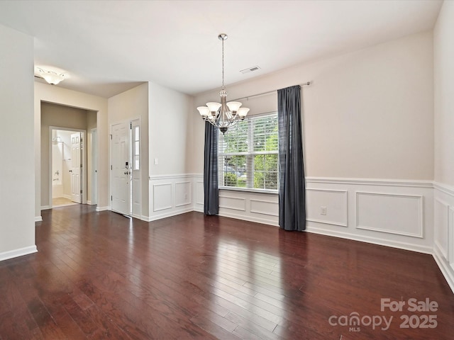 5355 Hackberry Ln SW, Concord, NC 28027 - unfurnished dining area featuring wainscoting, a decorative wall, a chandelier, visible vents, and hardwood / wood-style flooring