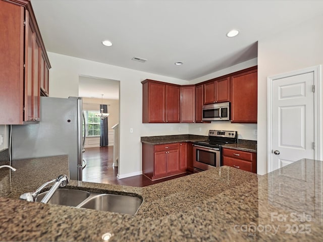 5355 Hackberry Ln SW, Concord, NC 28027 - kitchen featuring dark brown cabinets, a sink, dark stone counters, stainless steel appliances, and visible vents