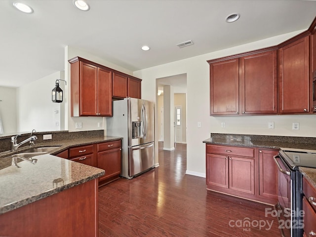 5355 Hackberry Ln SW, Concord, NC 28027 - kitchen featuring dark wood-style flooring, appliances with stainless steel finishes, a sink, reddish brown cabinets, and visible vents