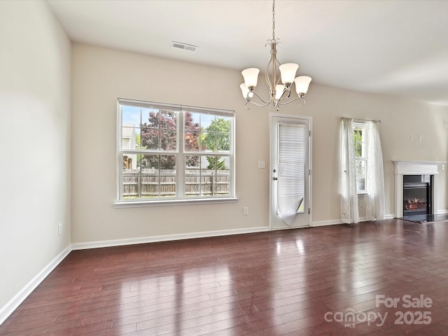 5355 Hackberry Ln SW, Concord, NC 28027 - unfurnished living room featuring a healthy amount of sunlight, wood-type flooring, a notable chandelier, and visible vents