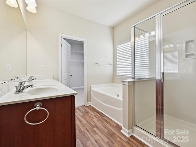 5355 Hackberry Ln SW, Concord, NC 28027 - bathroom featuring double vanity, a bath, a shower stall, wood finished floors, and a sink