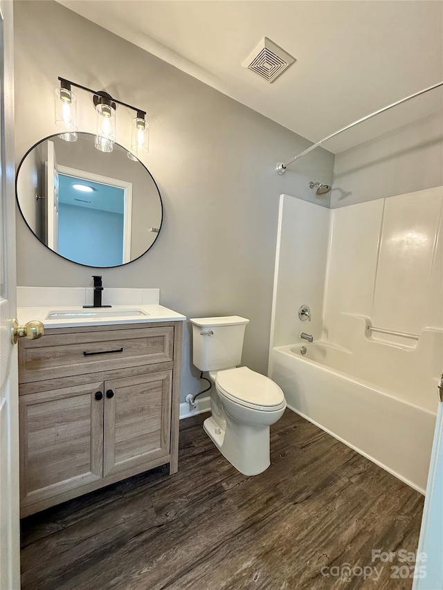 bathroom featuring wood finished floors, toilet, vanity, and  shower combination